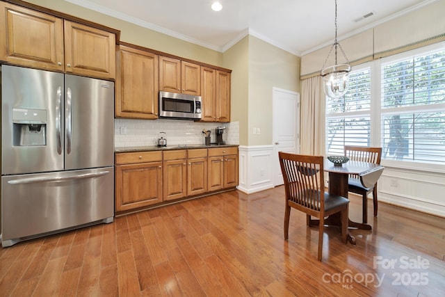 964 Knob Creek Ln, Fort Mill, SC 29708 - kitchen featuring appliances with stainless steel finishes, ornamental molding, a chandelier, wood finished floors, and brown cabinets