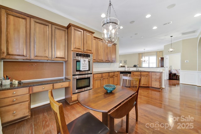 964 Knob Creek Ln, Fort Mill, SC 29708 - kitchen featuring stainless steel appliances, a peninsula, ornamental molding, a chandelier, and wood finished floors