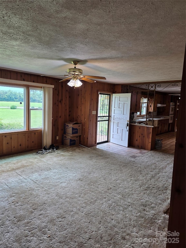 4298 NC-41 Hwy S, Fairmont, NC 28340 - unfurnished living room featuring a textured ceiling, wooden walls, carpet, and ceiling fan