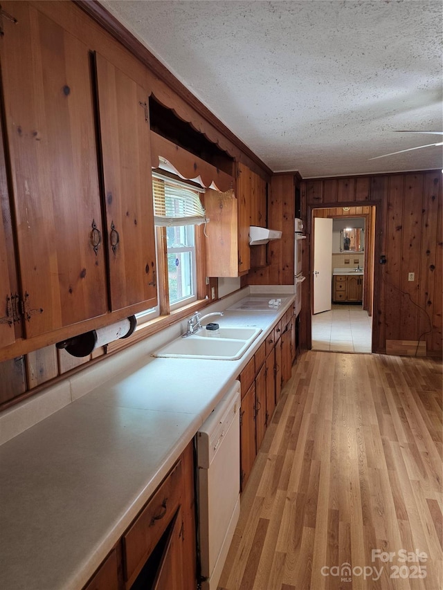 4298 NC-41 Hwy S, Fairmont, NC 28340 - kitchen with white dishwasher, light wood-style flooring, brown cabinetry, a sink, and a textured ceiling