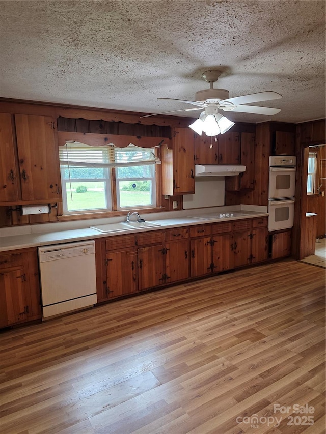 4298 NC-41 Hwy S, Fairmont, NC 28340 - kitchen featuring white appliances, a sink, under cabinet range hood, light wood-style floors, and brown cabinets