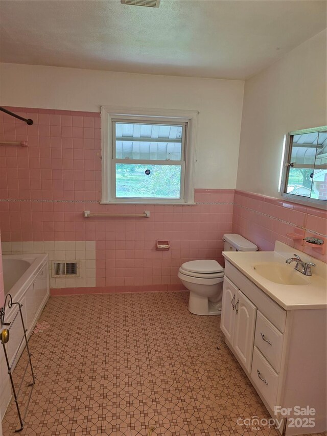 4298 NC-41 Hwy S, Fairmont, NC 28340 - bathroom featuring tile walls, vanity, toilet, wainscoting, and tile patterned floors