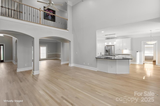 122 Long Cove Ln, Mooresville, NC 28117 - unfurnished living room featuring ceiling fan, baseboards, light wood-style floors, and a high ceiling