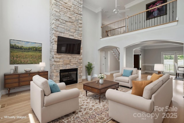 122 Long Cove Ln, Mooresville, NC 28117 - living area with arched walkways, a ceiling fan, ornamental molding, a high ceiling, and a stone fireplace