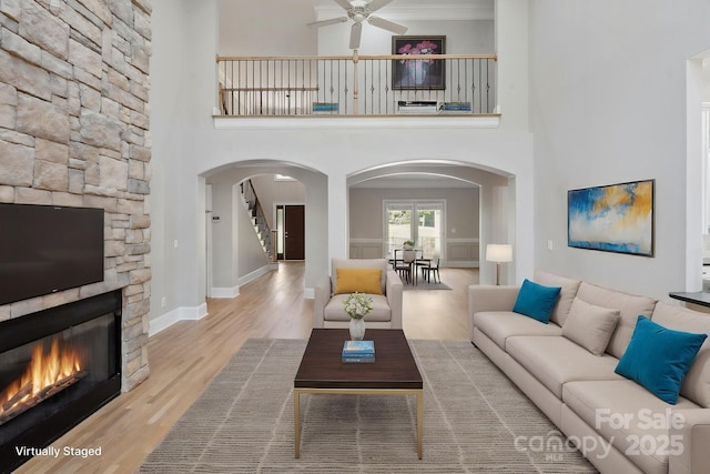 122 Long Cove Ln, Mooresville, NC 28117 - living room with arched walkways, a fireplace, a ceiling fan, wood finished floors, and stairway