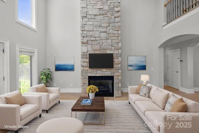 122 Long Cove Ln, Mooresville, NC 28117 - living area featuring a towering ceiling, arched walkways, baseboards, a fireplace, and wood finished floors