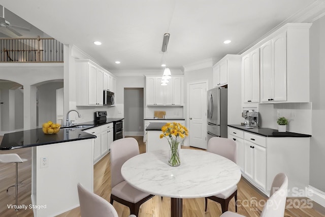 122 Long Cove Ln, Mooresville, NC 28117 - kitchen featuring a sink, appliances with stainless steel finishes, a peninsula, a kitchen bar, and dark countertops