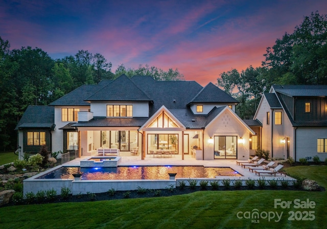 15037 June Washam Rd, Davidson, NC 28036 - back of property at dusk with a lawn, a patio area, a pool with connected hot tub, and a fire pit