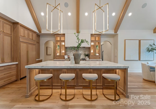 15037 June Washam Rd, Davidson, NC 28036 - kitchen featuring arched walkways, beam ceiling, a breakfast bar area, high vaulted ceiling, and a spacious island