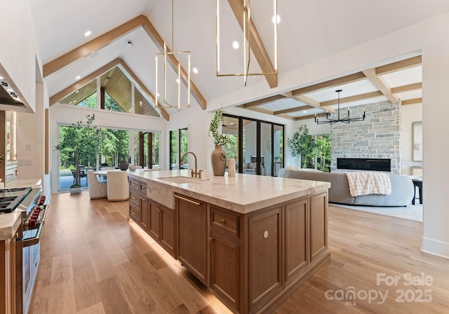 15037 June Washam Rd, Davidson, NC 28036 - kitchen featuring high end stainless steel range, open floor plan, brown cabinetry, a chandelier, and light wood-style floors