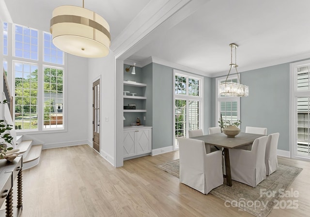 2921 Windsor Ave, Charlotte, NC 28209 - dining area featuring light wood-type flooring, a chandelier, plenty of natural light, built in features, and crown molding