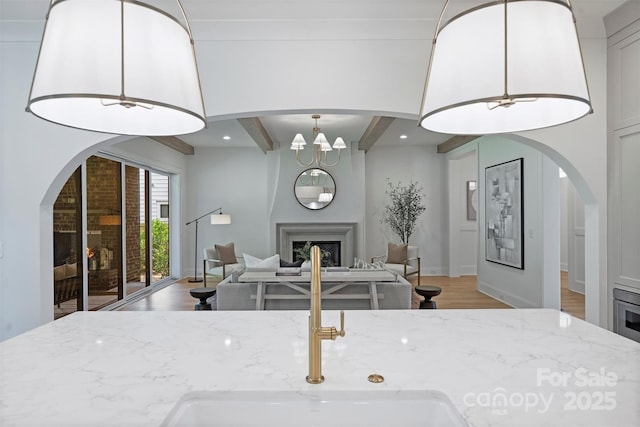 2921 Windsor Ave, Charlotte, NC 28209 - kitchen with light stone countertops, light wood-style flooring, beamed ceiling, a fireplace, and open floor plan