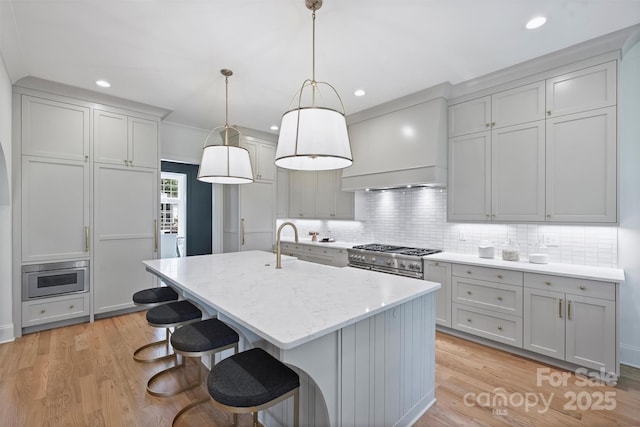 2921 Windsor Ave, Charlotte, NC 28209 - kitchen featuring premium range hood, high end stove, a center island with sink, decorative backsplash, and a kitchen bar