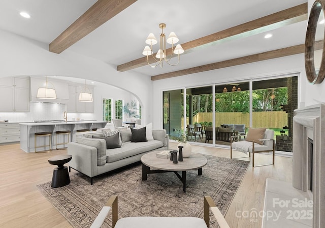 2921 Windsor Ave, Charlotte, NC 28209 - living room with a chandelier, beamed ceiling, arched walkways, light wood-type flooring, and recessed lighting
