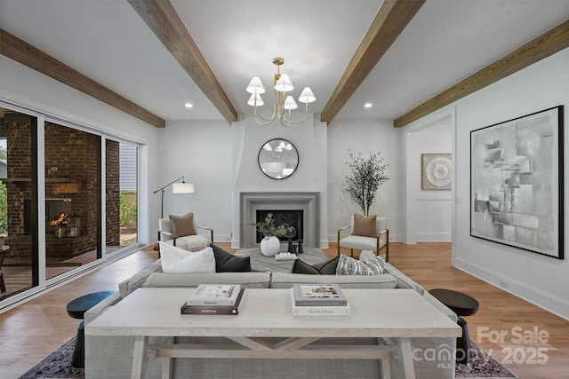 2921 Windsor Ave, Charlotte, NC 28209 - living room with a warm lit fireplace, beamed ceiling, a chandelier, wood finished floors, and recessed lighting