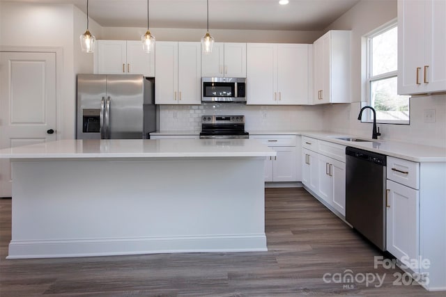 118 Durham Rd, Stanley, NC 28164 - kitchen featuring appliances with stainless steel finishes, a sink, a kitchen island, dark wood-style floors, and white cabinetry