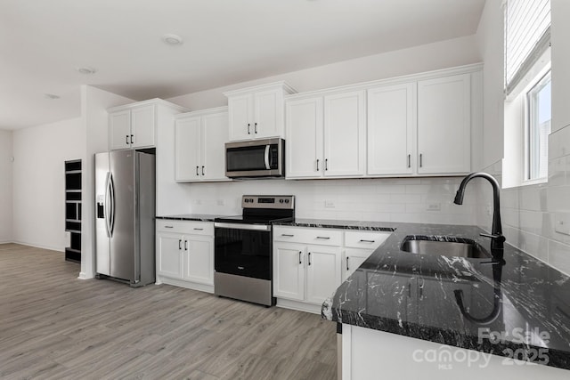 15034 Scoter St, Charlotte, NC 28262 - kitchen with stainless steel appliances, a sink, white cabinets, and light wood finished floors
