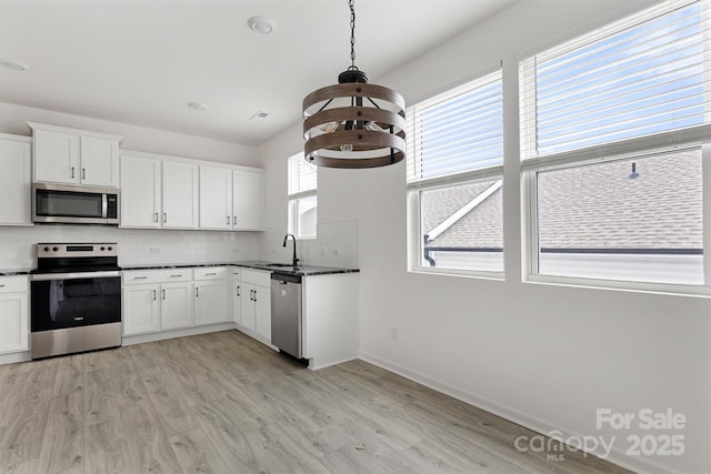 15034 Scoter St, Charlotte, NC 28262 - kitchen with stainless steel appliances, light wood-style flooring, tasteful backsplash, and white cabinets