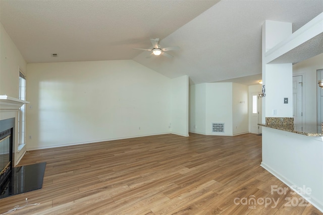 16 Red Barn Ln, Fletcher, NC 28732 - unfurnished living room with a ceiling fan, light wood-style floors, a glass covered fireplace, and lofted ceiling