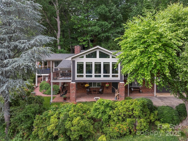95 Harmon Ave, Lake Junaluska, NC 28745 - back of property featuring a chimney, a patio area, a deck, a sunroom, and a shingled roof