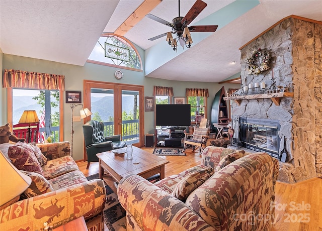 724 Pless Underwood Rd, Maggie Valley, NC 28751 - living room featuring vaulted ceiling, wood finished floors, a stone fireplace, a ceiling fan, and french doors