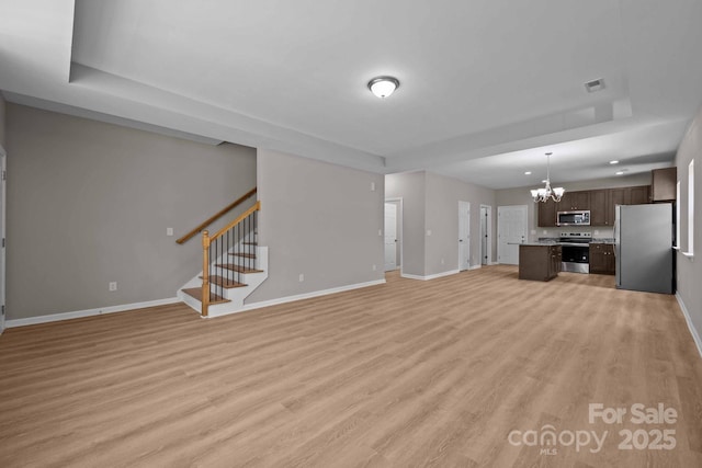 130 Aurora Blvd, Matthews, NC 28105 - unfurnished living room with a chandelier, light wood-style floors, stairs, a tray ceiling, and recessed lighting