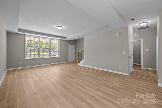 130 Aurora Blvd, Matthews, NC 28105 - unfurnished living room with a raised ceiling, stairway, and light wood-style floors