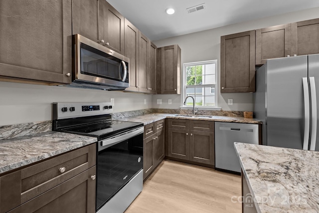 130 Aurora Blvd, Matthews, NC 28105 - kitchen featuring stainless steel appliances, light wood finished floors, dark brown cabinets, light stone countertops, and recessed lighting