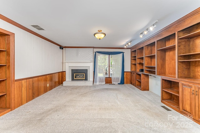 220 Blackberry Trl, Concord, NC 28027 - unfurnished living room featuring wooden walls, light carpet, crown molding, a fireplace, and a wainscoted wall