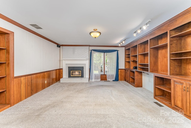 220 Blackberry Trl, Concord, NC 28027 - unfurnished living room featuring wood walls, light carpet, ornamental molding, a brick fireplace, and a wainscoted wall