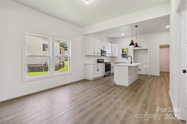 113 Woodside Ave, Gastonia, NC 28054 - kitchen with stainless steel appliances, light wood-type flooring, white cabinets, decorative light fixtures, and light countertops