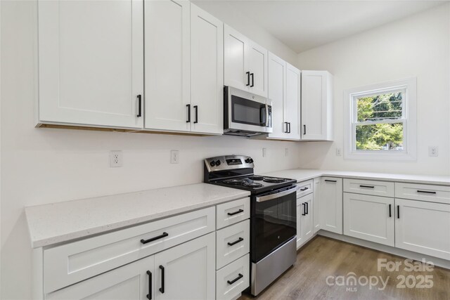 113 Woodside Ave, Gastonia, NC 28054 - kitchen featuring appliances with stainless steel finishes, white cabinetry, light wood-type flooring, and light stone countertops