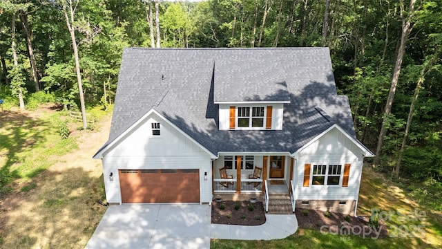 1004 E Sandy Ridge Rd, Monroe, NC 28112 - modern farmhouse featuring a porch, driveway, crawl space, a garage, and a view of trees