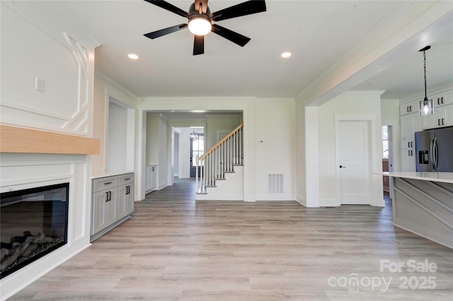 102 Starmount Dr, Kings Mountain, NC 28086 - unfurnished living room featuring stairs, ornamental molding, ceiling fan, light wood finished floors, and a glass covered fireplace