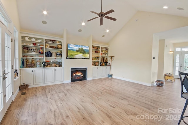 30 Linn Garden Ln, Swannanoa, NC 28778 - unfurnished living room with light wood finished floors, a warm lit fireplace, ceiling fan, french doors, and high vaulted ceiling