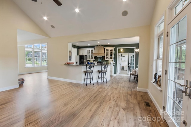 30 Linn Garden Ln, Swannanoa, NC 28778 - kitchen with stainless steel fridge, custom range hood, a kitchen bar, light wood-type flooring, and glass insert cabinets