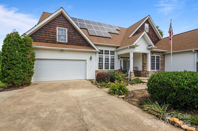 30 Linn Garden Ln, Swannanoa, NC 28778 - view of front of house with roof mounted solar panels, driveway, covered porch, a shingled roof, and stone siding