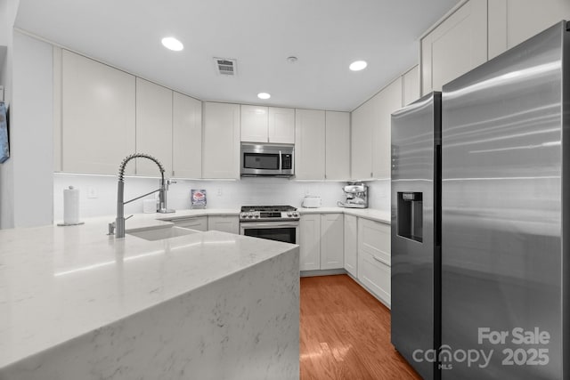 415 N Church St Unit 311, Charlotte, NC 28202 - kitchen with appliances with stainless steel finishes, light wood-style flooring, white cabinetry, light stone counters, and recessed lighting