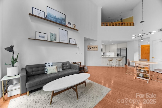 415 N Church St Unit 311, Charlotte, NC 28202 - living area with light wood-style floors, a chandelier, and a high ceiling