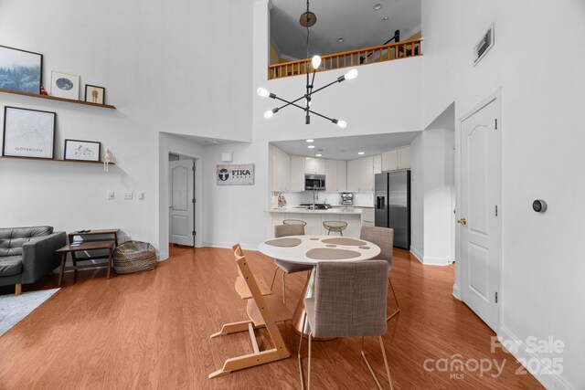 415 N Church St Unit 311, Charlotte, NC 28202 - dining area with wood finished floors, a chandelier, and a high ceiling