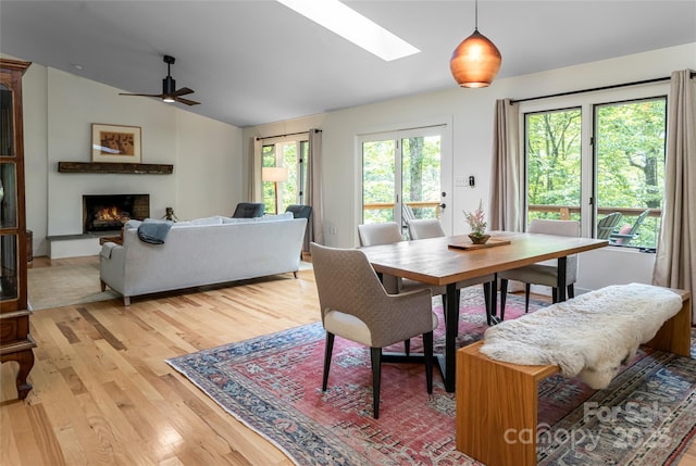 12 Beech Tree Ln, Asheville, NC 28804 - dining space with vaulted ceiling, a skylight, light wood-style flooring, a lit fireplace, and a ceiling fan