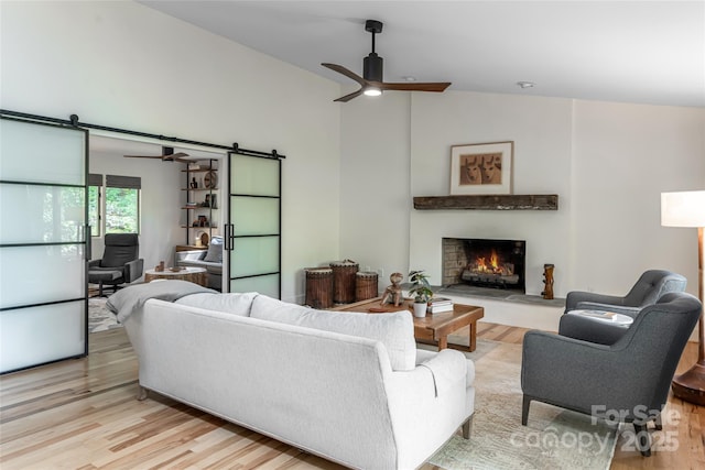 12 Beech Tree Ln, Asheville, NC 28804 - living room featuring a barn door, a ceiling fan, light wood finished floors, a warm lit fireplace, and lofted ceiling