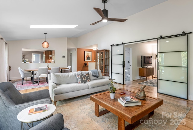 12 Beech Tree Ln, Asheville, NC 28804 - living room featuring vaulted ceiling, a barn door, ceiling fan, and light wood-style flooring
