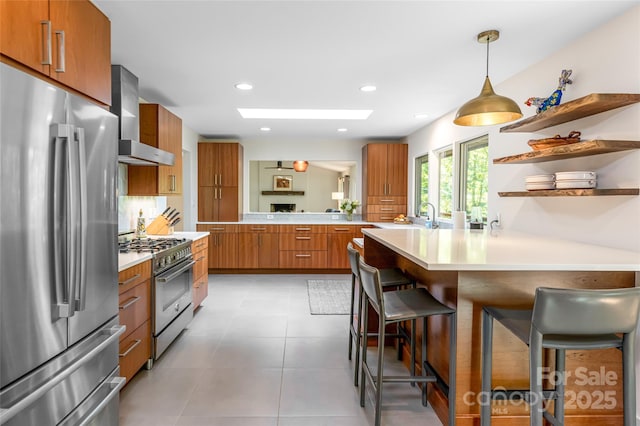12 Beech Tree Ln, Asheville, NC 28804 - kitchen with appliances with stainless steel finishes, wall chimney range hood, brown cabinetry, a peninsula, and light countertops