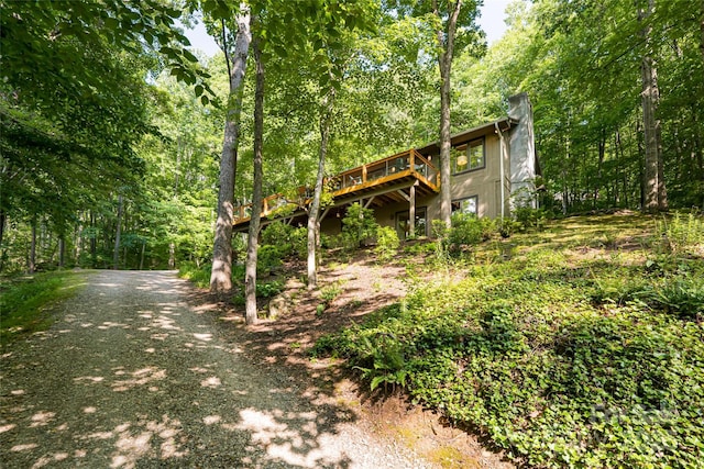 12 Beech Tree Ln, Asheville, NC 28804 - exterior space featuring a deck, a wooded view, a chimney, and dirt driveway
