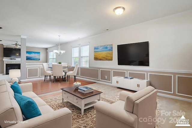 8915 Merrie Rose Ave, Charlotte, NC 28213 - living area with a decorative wall, crown molding, a ceiling fan, a chandelier, and wainscoting