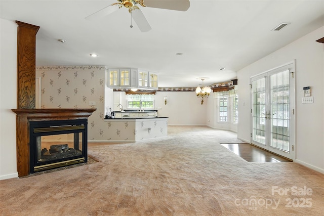 441 Wildlife Club Ln, Taylorsville, NC 28681 - unfurnished living room featuring light carpet, baseboards, ceiling fan, a multi sided fireplace, and a chandelier