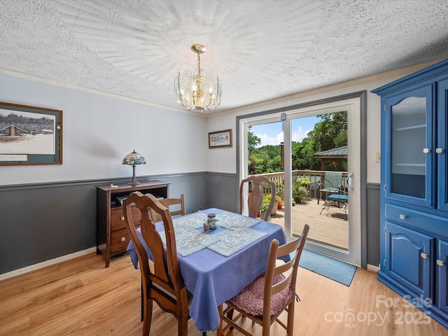 3509 Flint Dr, Statesville, NC 28677 - dining area featuring light wood finished floors, a chandelier, a textured ceiling, and wainscoting
