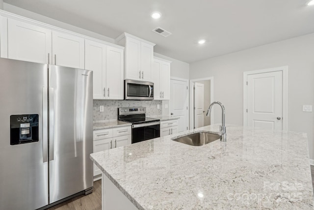 108 Ciara Pl Unit E, Mooresville, NC 28117 - kitchen featuring appliances with stainless steel finishes, a sink, a center island with sink, white cabinets, and light wood-type flooring