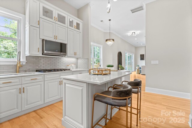 4015 Randolph Rd, Charlotte, NC 28211 - kitchen with stainless steel appliances, light wood-style flooring, a kitchen bar, tasteful backsplash, and a center island